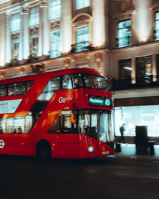 A red double-decker bus traveling on a street in Marylebone, London, with ornate classical-style buildings featuring large windows, decorative columns, and detailed stonework illuminated by warm lighting in the background. The bus displays route number 43 to Marylebone, and the scene captures a typical urban environment, emphasizing the vibrant city atmosphere. The image reflects the busy, clean streets typical of Marylebone, aligning with the theme of residential and commercial cleaning tips promoted by Marylebone Cleaners on their website.