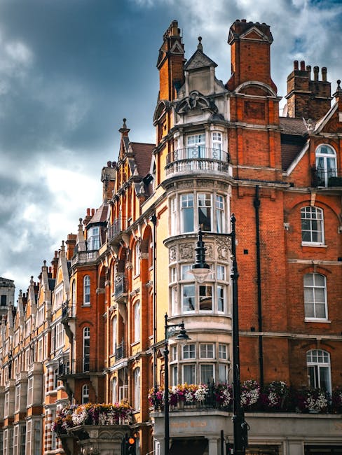 Image of a historic red-brick residential building in Marylebone, featuring multiple large sash windows with white frames and black wrought iron railings. The building has a variety of architectural d